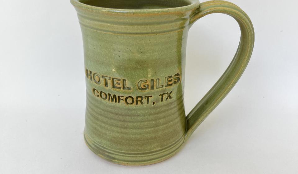 Hotel Giles green ceramic mug, logo to front when held in left hand