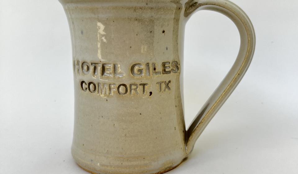 Hotel Giles white ceramic mug logo to front when held in left hand