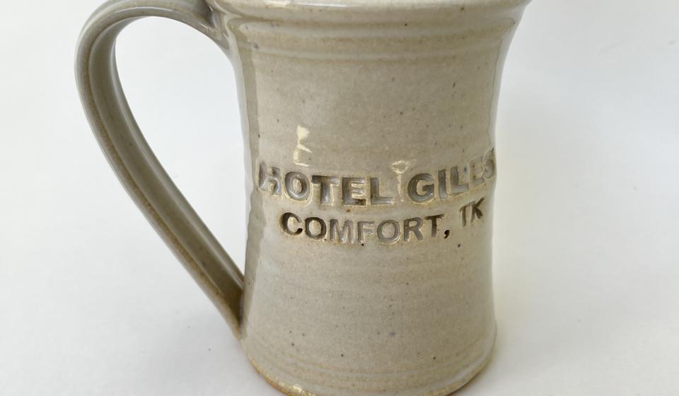 Hotel Giles white ceramic mug logo to front when held in right hand