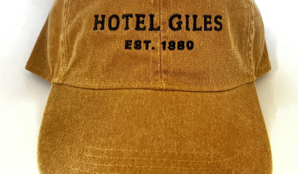 Tan fabric adjustable cap with cream embroidered Hotel Giles logo